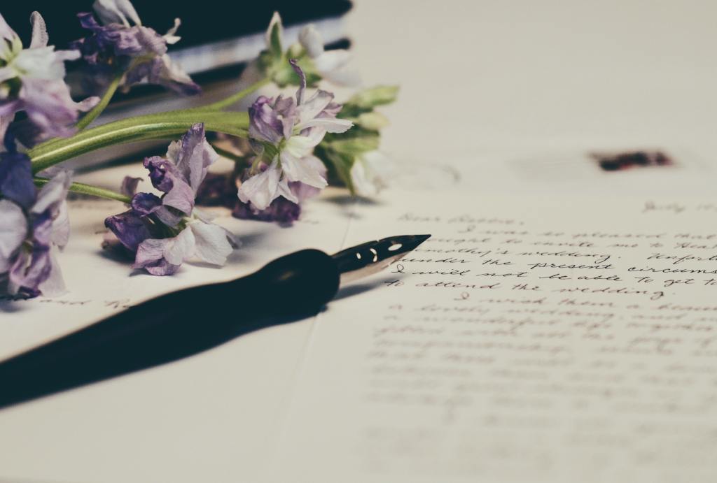 fountain pen over a handwritten letter with purple flowers